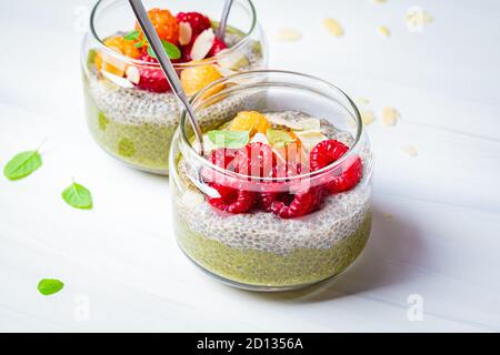 Chia Pudding mit Matcha-Tee und Beeren im Glas, weißer Hintergrund. Gesunde Ernährung Konzept. Stockfoto
