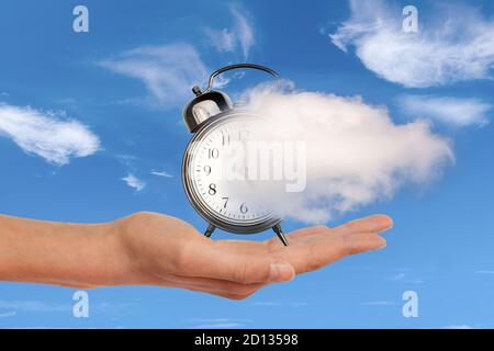 Hand, die eine Uhr hält, die sich in einer Wolke auflöst. Zeit vergeht, Zeitmanagement-Konzept. Surreale Collage. Stockfoto