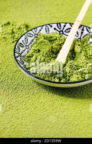 Grüner Tee matcha Pulver in Keramik Schüssel mit traditionellen Bambus matcha Löffel über Pudern als Hintergrund. Stockfoto