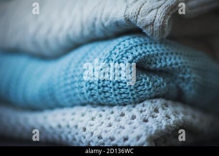 Drei warme Strickpullover mit Mustern, von denen einer blau ist, sind ordentlich gestapelt. Warme Kleidung für kalte Zeiten vorbereitet. Winter und Herbst. Stockfoto