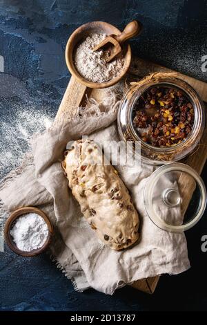 Christmas Cake, traditionelle deutsche Festliches backen. Vollkorn Teig stollen Vorbereitung auf Leinen Serviette mit Schalen von Mehl und Rosinen über Dunkelblau Stockfoto