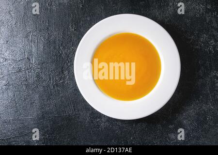 Platte von vegetarisch vegan Kürbis Karotten Suppe über schwarzen Textur Hintergrund. Flach, kopieren Raum Stockfoto