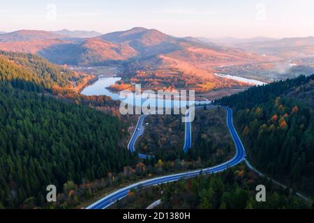 Antenne drone Blick über den Herbst in den Bergen mit Mountain Road Serpentine, Fluss und Wald. Landschaftsfotografie Stockfoto