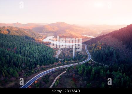 Antenne drone Blick über den Herbst in den Bergen mit Mountain Road Serpentine, Fluss und Wald. Landschaftsfotografie Stockfoto