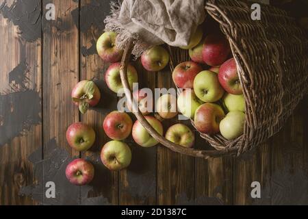 Reif im Garten Grün rote Äpfel in alten Korb mit Tuch über dunkle Plank Holz- Hintergrund. Flach, Platz. Herbst Ernte. Stockfoto