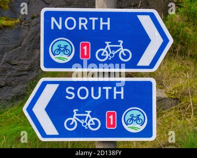 Zwei weiße auf blaue Schilder für die UK National Cycle Route 1 in Lerwick, Shetland, Schottland, Großbritannien - eine Richtung Norden, die andere Richtung Süden. Stockfoto