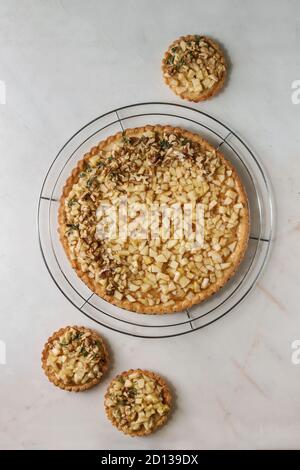 Hausgemachten süßen Apfel Walnüsse shortbread tart auf Kühlung Rack und Törtchen mit weißem Marmor Hintergrund. Herbst backen. Flach, Raum Stockfoto