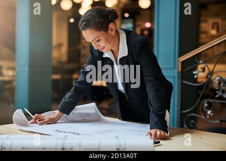 Fröhliche Brünette Frau starrte auf ihre Skizze Stockfoto