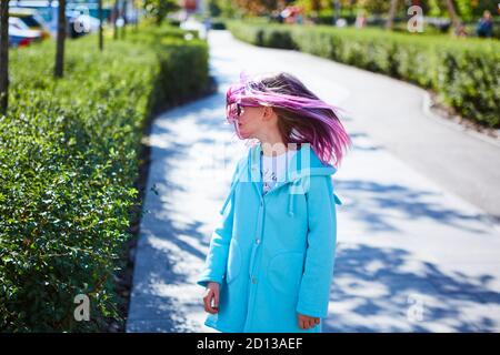 Mädchen 8 Jahre alt mit rosa Haar springen im Freien Stockfoto