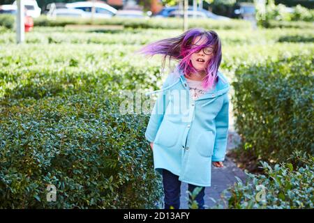 Mädchen 8 Jahre alt mit rosa Haar springen im Freien Stockfoto