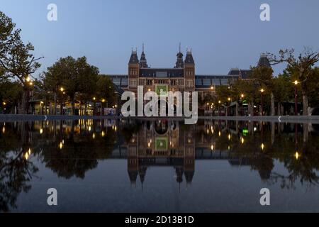 AMSTERDAM, NIEDERLANDE - 22. Sep 2020: Blauer Sonnenuntergang im historischen Kunstmuseum Rijksmuseum mit Straßenlaternen, die sich in dem ruhigen Teich in der Stadt spiegeln Stockfoto