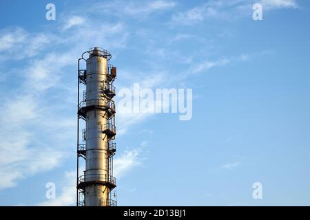 Alte Destillationskolonne Türme mit blauem Himmel mit Wolken Hintergrund bei chemischen Anlage. Außenansicht von Silber Metall rostigen Methanol Destillation Unternehmen Stockfoto