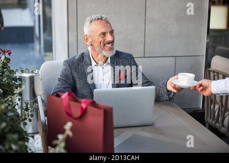 Fröhliche Senioren mit einem Laptop mit einer Tasse Tee Stockfoto