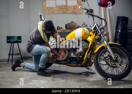 Ein starker Biker repariert sein Motorrad in der Garage. Der Innenraum der Werkstatt Stockfoto