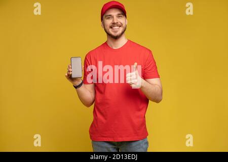 Junger Mann hält Smartphone isoliert auf gelb. Stockfoto