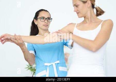 Frau Arzt Physiotherapeut hält Hand an Frau Patientin in weiß Kleidung Porträt Stockfoto