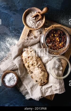 Christmas Cake, traditionelle deutsche Festliches backen. Vollkorn Teig stollen Vorbereitung auf Leinen Serviette mit Schalen von Mehl und Rosinen über Dunkelblau Stockfoto