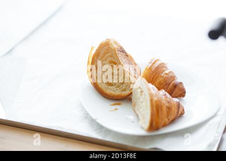 Frisch gebackenes Croissant in Stücke geschnitten auf weißem Teller Stockfoto