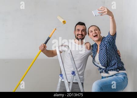 Ein verheiratetes Paar nimmt ein Selfie auf dem Handy während Sie machen Reparaturen Stockfoto