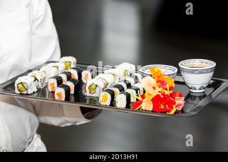 Sushi-Vorspeisen auf einem Tablett, das von einem Kellner gehalten wird Stockfoto