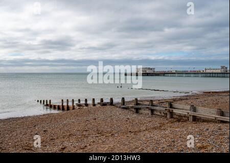 Blick nach Westen zum Worthing Pier über den Strand mit hölzernen Rallen, die zum Schutz vor Meereserosion angeordnet sind. West Sussex, Großbritannien. Stockfoto