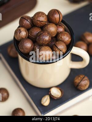 Eine Handvoll Macadamianüsse aus der Nähe in einem Becher auf hellem Hintergrund. Stockfoto
