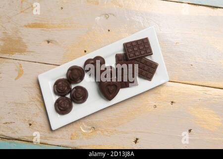 Handgemachte Schokolade aus dunkler Schokolade auf Holztisch, Draufsicht. Stockfoto