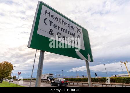 Schild für Heathrow Airport, London, UK, Terminal 4 und Fracht, mit einem Düsenflugzeug Landung, über A30 Straße. Ankunft am Abend über dem Auto Stockfoto