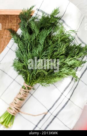Ein paar frische Dill-Grüns auf einem Küchentuch auf einem Holzbrett. Food-Foto. Stockfoto