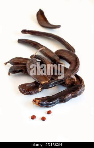 Trockene Johannisbrotschoten und Samen schließen isoliert auf Weiß Stockfoto