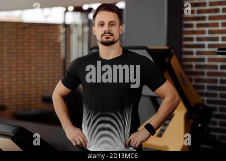 Portrait des persönlichen Trainers im Sportoutfit im Fitness-Center Fitnessstudio steht stark Stockfoto