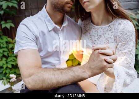 Ein Mann und eine Frau in weißen Kleidern umarmen. Die Hände der Menschen sind miteinander verflochten. Stockfoto