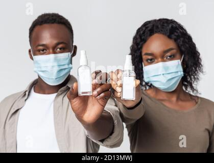 Junges Paar in Gesichtsmasken zeigt antiseptisch Stockfoto