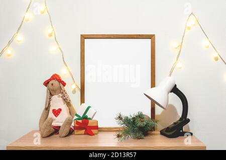 Weihnachten Poster Rahmen Modell. Hand gemacht Puppe grün Tanne Zweige rot Papier Geschenkboxen Lichter Girlande Lampe Stockfoto