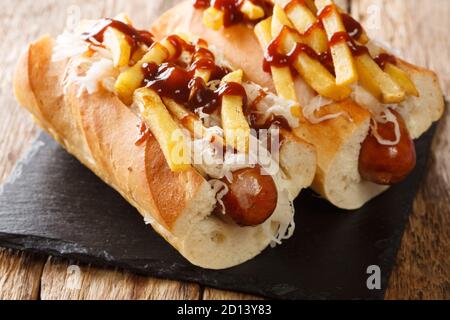 Köstliche Hot Dog Polish Boy mit Wurst, Kohl, Pommes frites und Grill-Sauce close-up auf dem Tisch. Horizontal Stockfoto