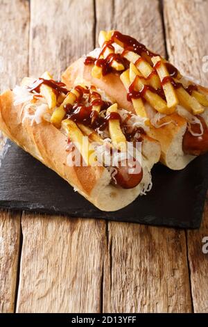 American Hot Dog Polish Boy mit Wurst, Kohl und Pommes frites close-up auf dem Tisch. Vertikal Stockfoto