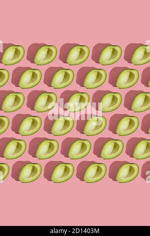 Trending Stil Muster der Hälfte seedless grün Avocado auf rosa Hintergrund mit hartem Licht. Kreative Lebensmitteltextur Stockfoto