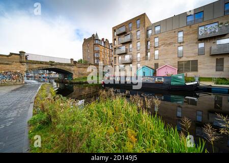 Moderne Wohnblocks und schmale Boote, die am Union Canal bei Fountainbridge in Edinburgh, Schottland, Großbritannien, festgemacht sind Stockfoto