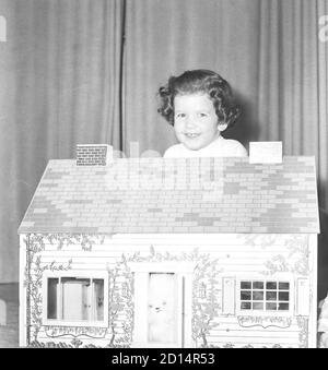 Junges Mädchen spielt mit ihrem Puppenhaus, USA 1950er Jahre Stockfoto