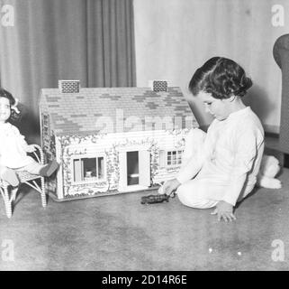 Junges Mädchen spielt mit ihrem Puppenhaus, USA 1950er Jahre Stockfoto