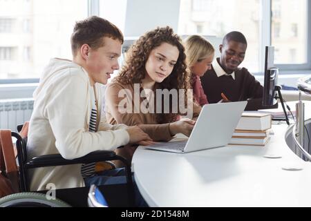 Seitenansicht der multiethnischen Gruppe von Studenten mit Laptop während des Studiums in der Hochschule, mit Jungen im Rollstuhl Stockfoto