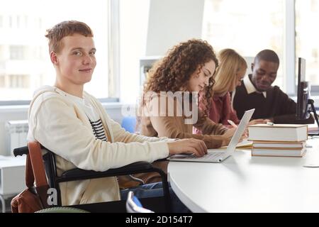 Porträt einer multiethnischen Gruppe von Studenten, die Laptops während des Studiums in der Hochschule, mit fröhlichen Jungen mit Rollstuhl Blick auf die Kamera Stockfoto