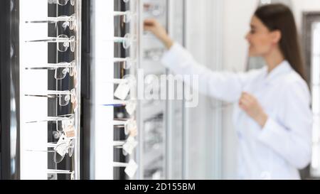 Optiker, der sich das Brillensortiment auf dem Display-Regal ansieht Stockfoto