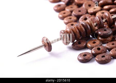 Holzperlen auf weißem Hintergrund mit Nadel verteilt. Perlen mit Nadel . Nahaufnahme, Makro. Stockfoto