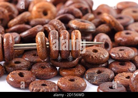 Holzperlen auf weißem Hintergrund mit Nadel verteilt. Perlen mit Nadel . Nahaufnahme, Makro. Stockfoto