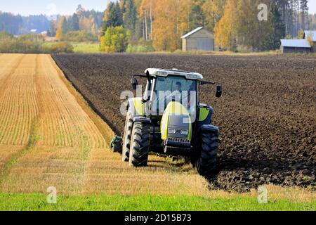 Bauer Pflügefeld mit grünen Valtra Traktor und Pflügen an einem sonnigen Herbstnachmittag in Südfinnland. Jokioinen, Finnland. Oktober 2020 Stockfoto