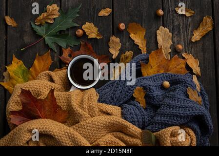 Flach Lay Herbst oder Herbst Zusammensetzung auf Holz rustikalen Hintergrund. Draufsicht auf Tasse Kaffee, gestrickte Tücher, gefallene Blätter und Haselnüsse. Gemütlich, warm, r Stockfoto