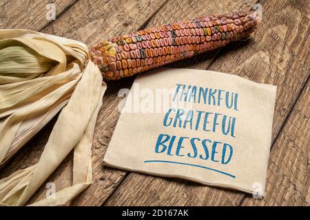 Dankbare, dankbare, gesegnete geistliche Worte - Handschrift auf Serviette mit ornamentalen Mais Agains verwittertes Holz, Thanksgiving-Konzept oder Gruß c Stockfoto