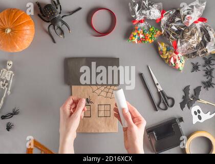 Schritt-für-Schritt-Verpackung eines Geschenks für Halloween. Schritt 12 - Klebe die Plastikspinne an Stockfoto