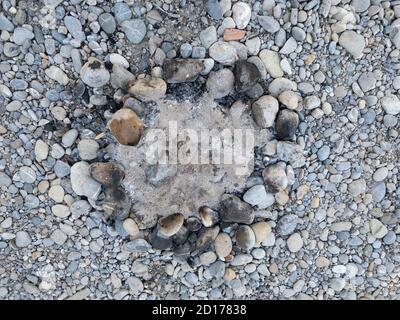 Ausgelöschter Kamin mit verkohltem Holz und Ruß auf den Steinen direkt von oben fotografiert am Tag, ohne Menschen Stockfoto